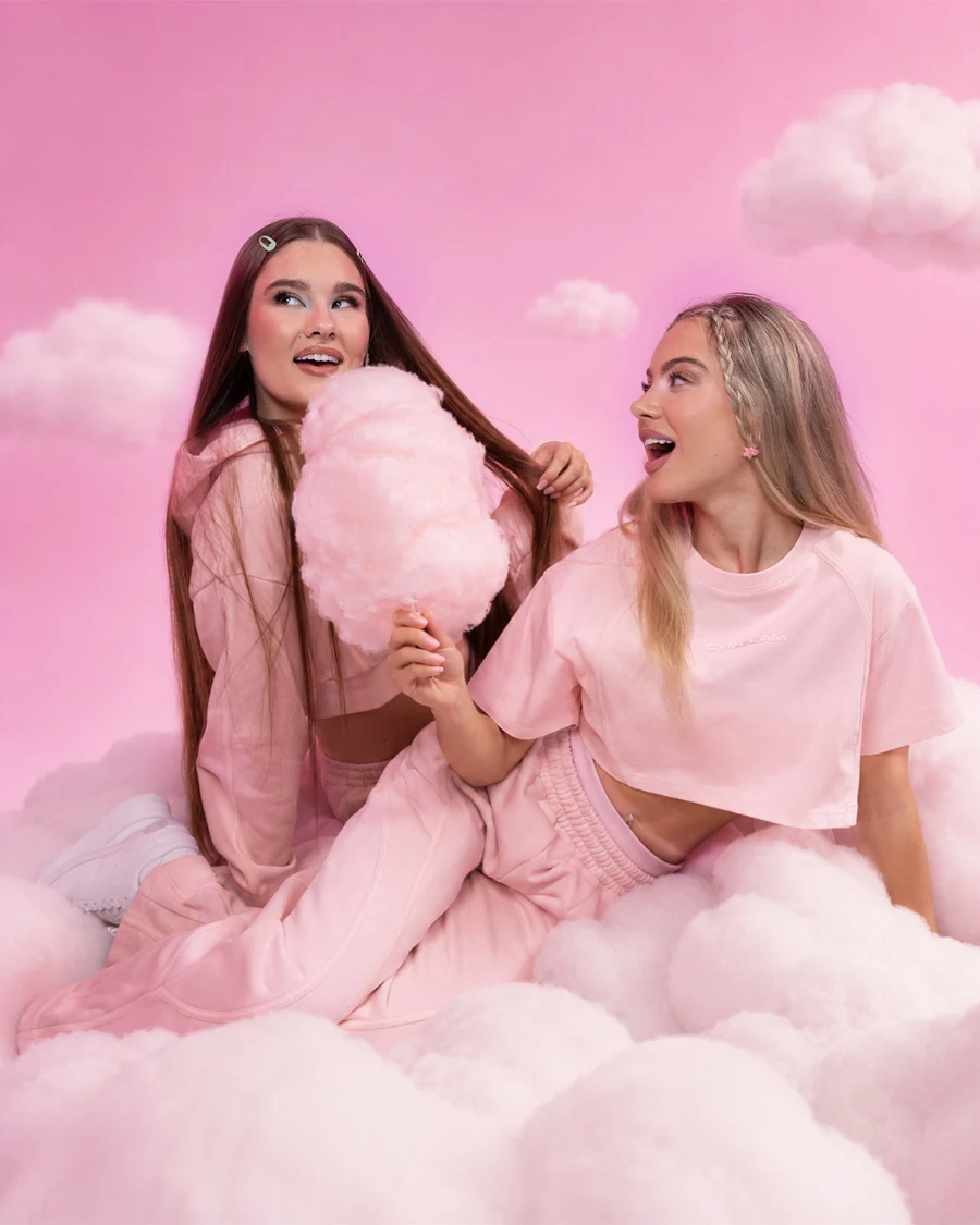 Zwei GymBeam-Models in rosa Outfits zwischen Wolken
